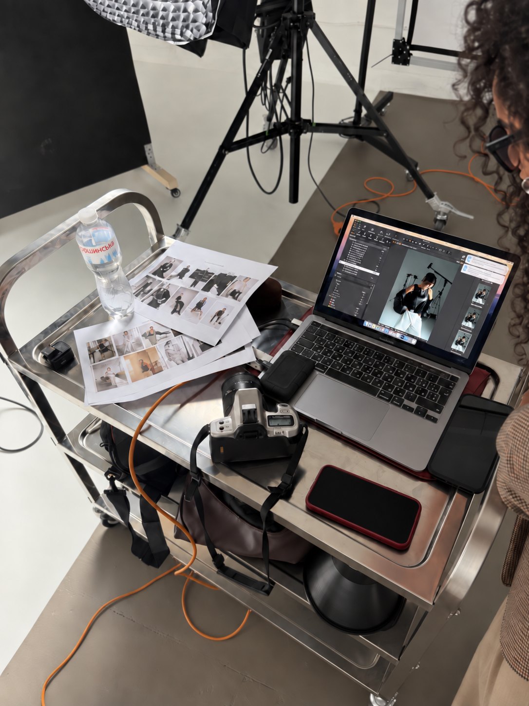 A photo shoot in progress: camera, lighting rig, contact sheets and a laptop mid-edit.
